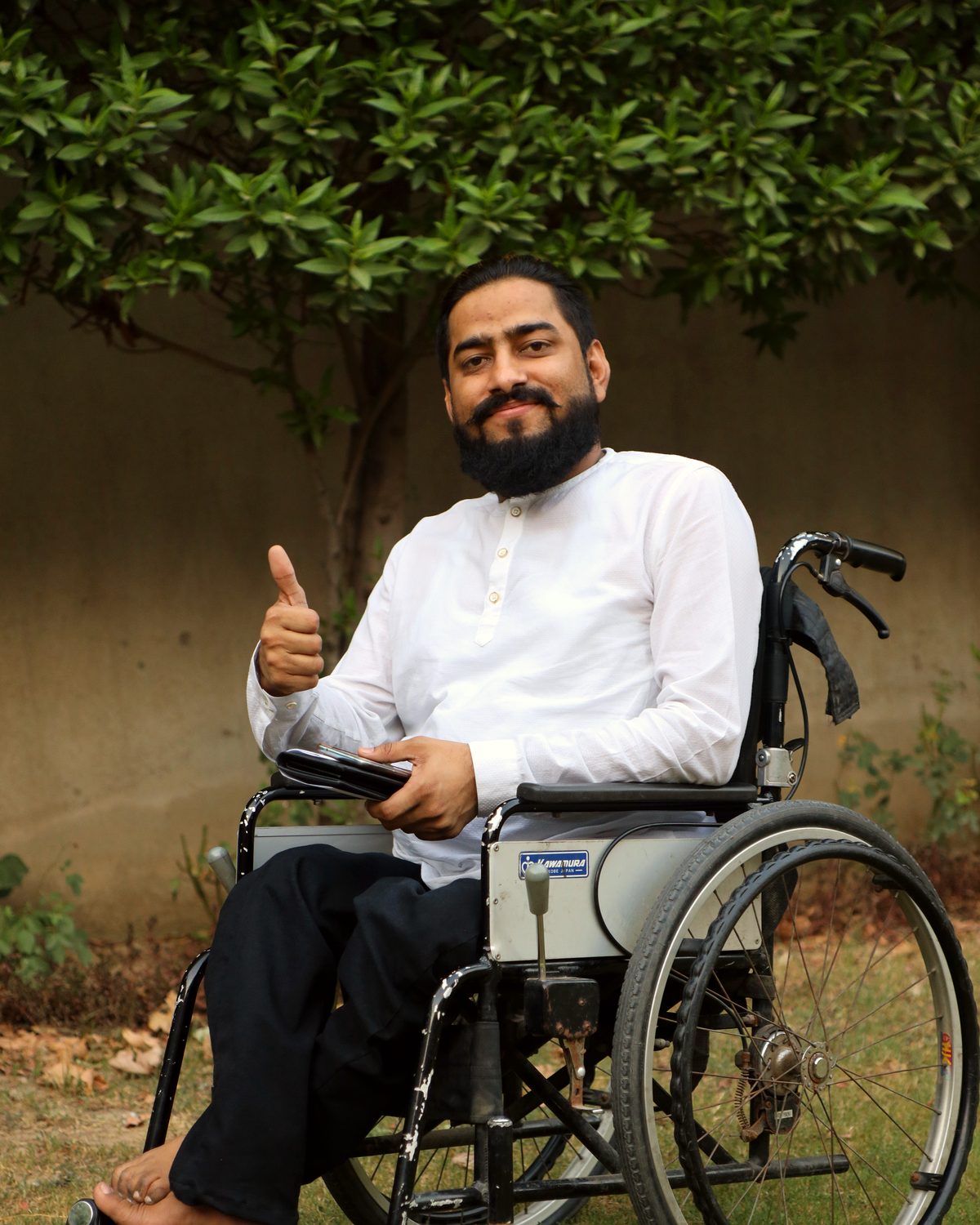 Raheel Nawaz giving a thumbs up from his wheelchair