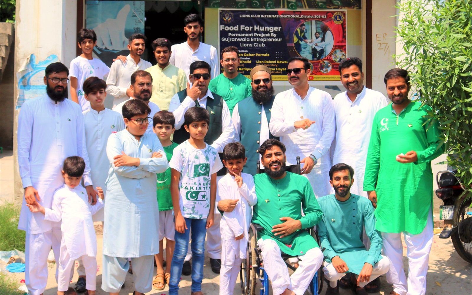 Raheel Nawaz in his wheelchair surrounded by children and Lions Club members at a community event